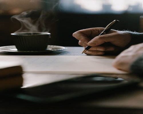 Hands holding a warm cup of coffee while reading a letter